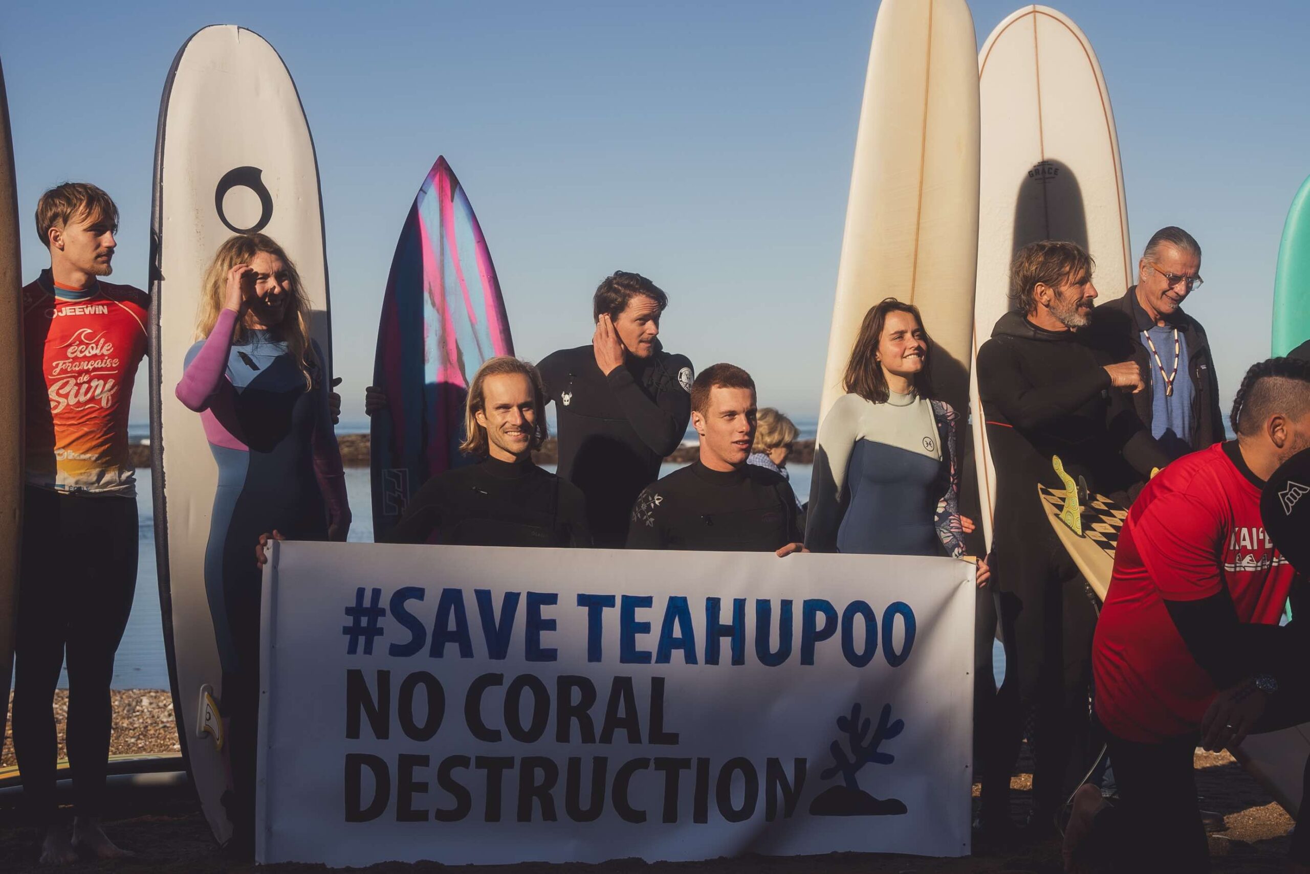 Les surfeurs tiennent une affiche "Save Teahupoo, no coral destruction"